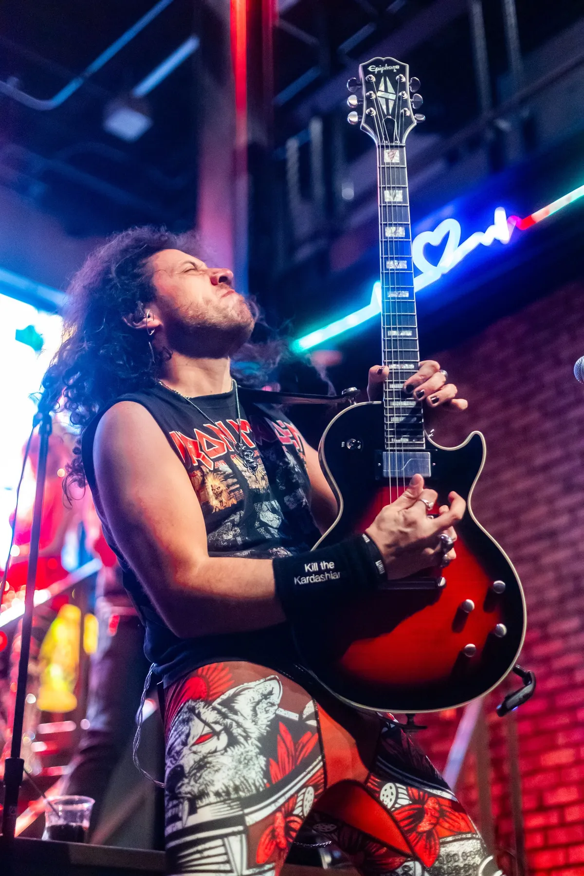 The guitarist playing a red SG under neon signage