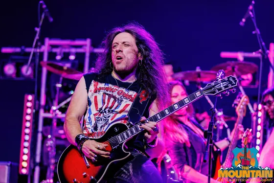 Diego Latorre singing while playing a sunburst Epiphone guitar in magenta stage light
