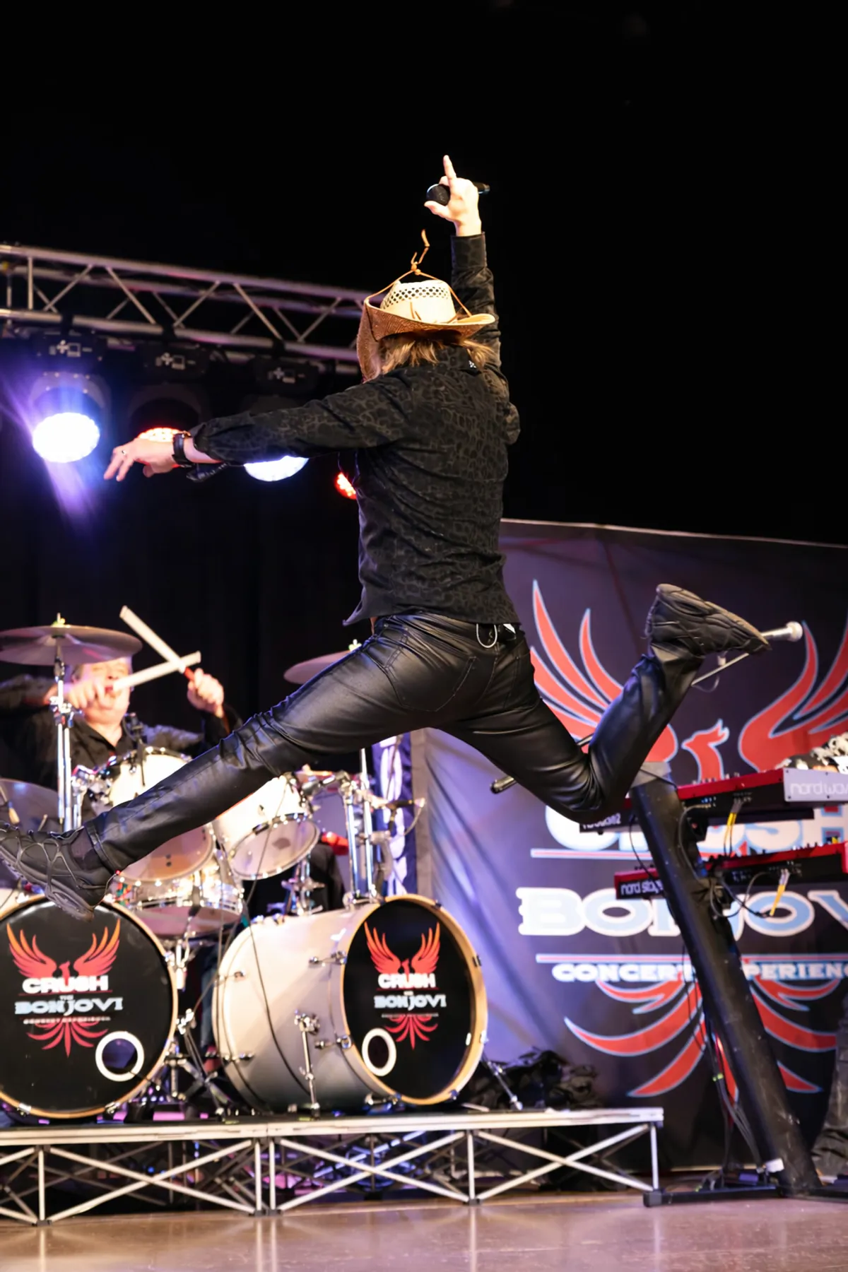 Doug Shepard mid-jump above the stage, arm pointed at the crowd