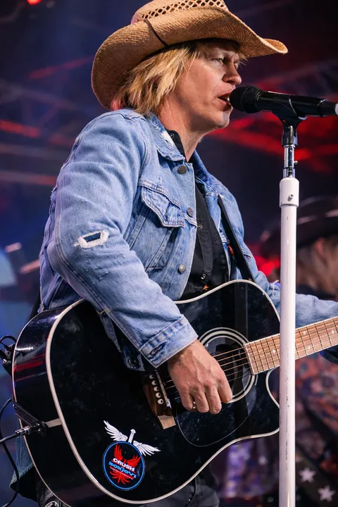 Doug Shepard in a cowboy hat playing acoustic guitar at the mic