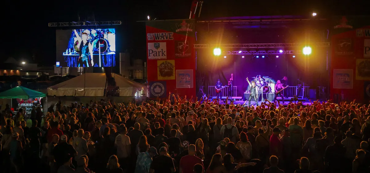 A packed festival field at dusk facing the lit stage